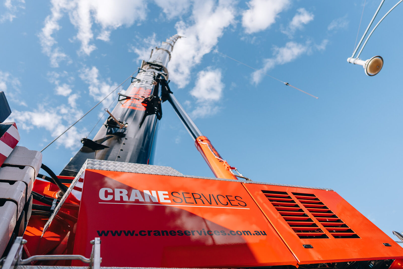 Night work: an operator at the crane outrigger controls, oversize and left-hand-drive signs on the deck beside them.