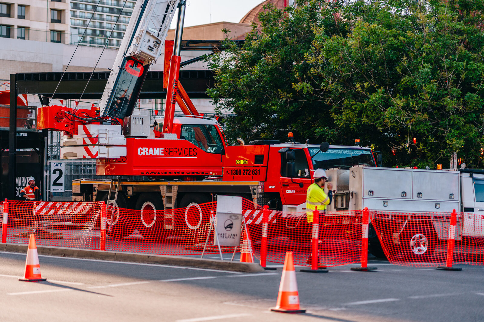 A giant figure boot on a flatbed truck below a red-brick tower, the crane boom above it.